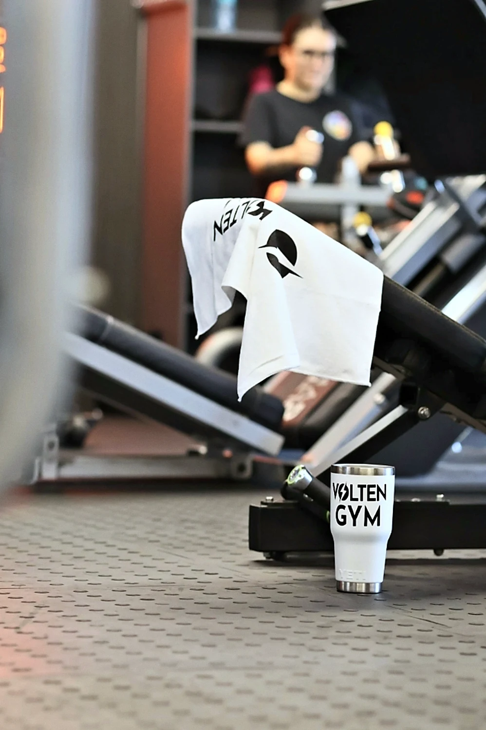 Toalla y termo con la marca Volten Gym junto a una máquina